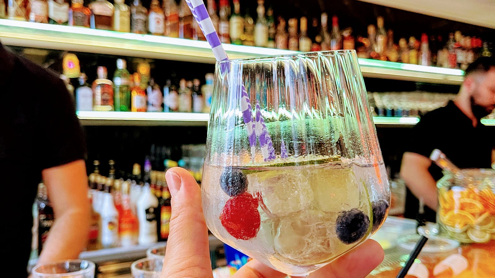 Cocktail in Nahaufnahme an der Bar, Barkeeper im Hintergrund
